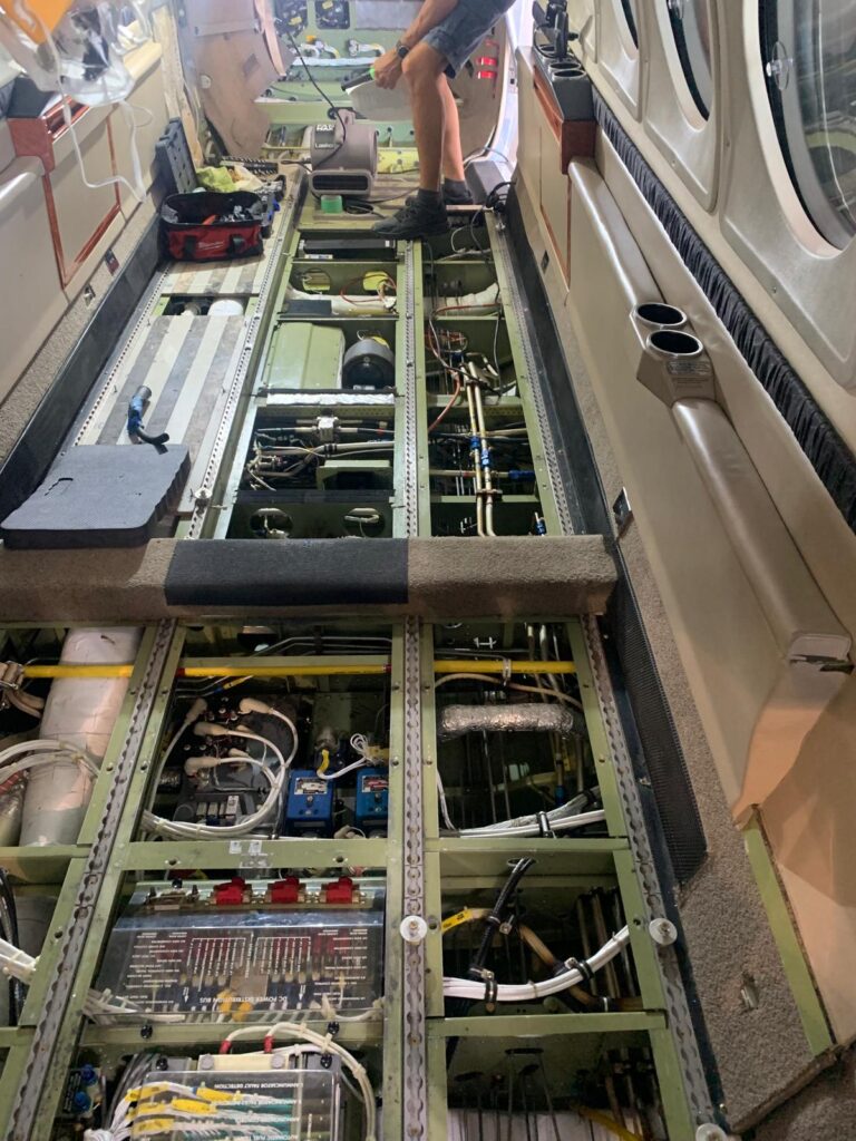 Aircraft interior exposed showing structural components, wiring, and systems during reconstruction work